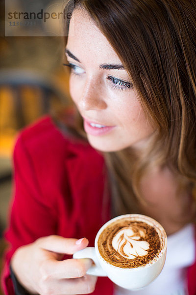 Nahaufnahme einer jungen Frau mit Cappuccino im Cafe