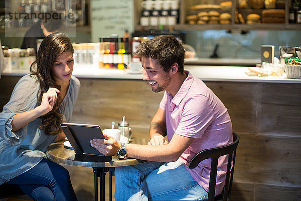 Junges Paar im Café betrachtet digitales Tablett