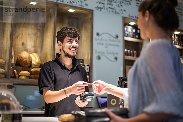 Barista übergibt Kreditkarte an weibliche Kundin am Café-Schalter