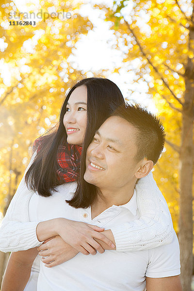 Junge Frau  die von ihrem Freund im Herbstpark huckepack von ihrem Freund zurückbekommt  Peking  China