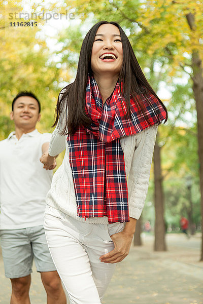 Junge Frau  die ihren Freund im Herbstpark an der Hand zieht  Peking  China
