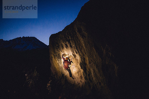 Junger Mann klettert nachts am Fels  Buttermilk Boulders  Bishop  Kalifornien  USA