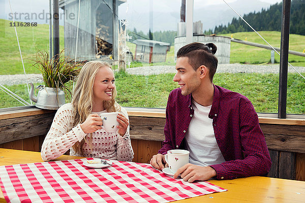 Junges Paar trinkt Kaffee und unterhält sich im Café