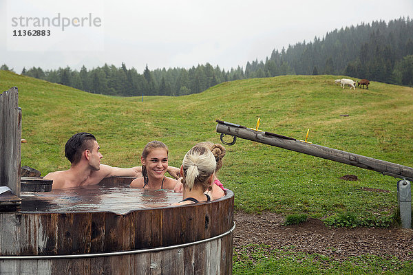 Vier erwachsene Freunde entspannen sich im ländlichen Whirlpool  Sattelbergalm  Tirol  Österreich
