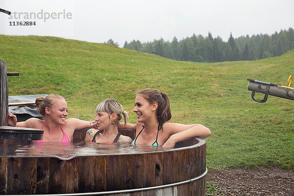 Drei Freundinnen lachen beim Entspannen im ländlichen Whirlpool  Sattelbergalm  Tirol  Österreich
