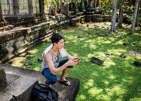 Mann hockt mit Smartphone in der Hand  Phimeanakas-Tempel  Siem Reap  Kambodscha
