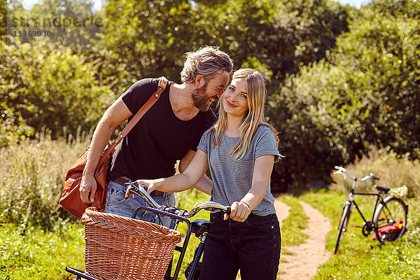 Porträt eines Paares mit lachenden Fahrrädern auf ländlichem Feldweg