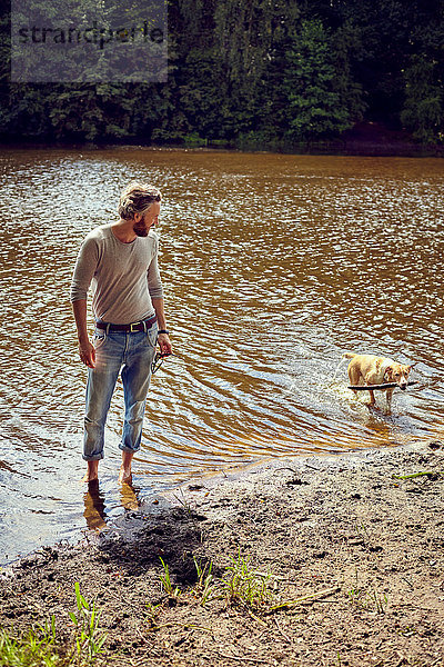 Mittelgroßer erwachsener Mann spielt mit Hund im Fluss