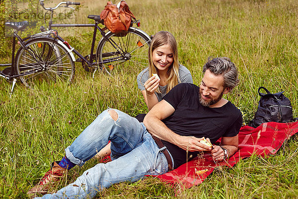 Ehepaar isst Äpfel beim Picknick auf dem Feld