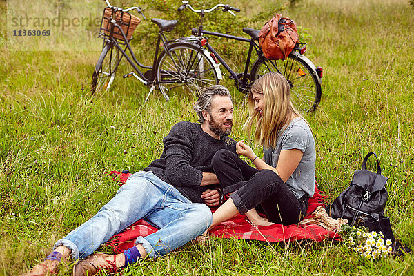 Romantisches Paar sitzt beim Picknick auf dem Feld