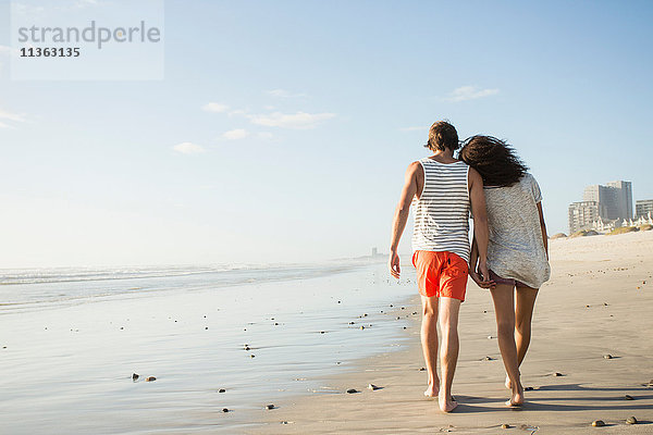 Rückansicht eines romantischen jungen Paares beim Strandspaziergang  Kapstadt  Western Cape  Südafrika