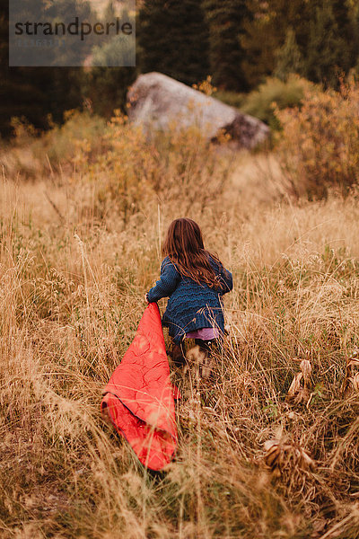 Junges Mädchen rennt durch langes Gras  schleppt Schlafsack  Rückansicht  Mineral King  Sequoia National Park  Kalifornien  USA