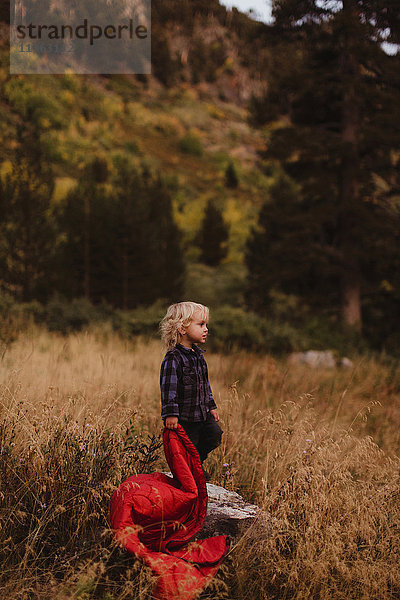 Auf dem Feld stehender Junge mit Schlafsack in der Hand  Mineral King  Sequoia National Park  Kalifornien  USA