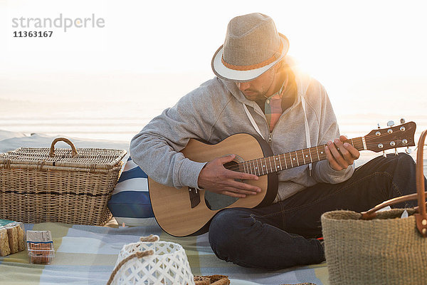Junger Mann spielt Gitarre am sonnenbeschienenen Strand  Kapstadt  Western Cape  Südafrika