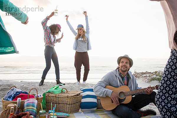 Junger Mann spielt Gitarre und Freundinnen tanzen am Strand  Kapstadt  Western Cape  Südafrika