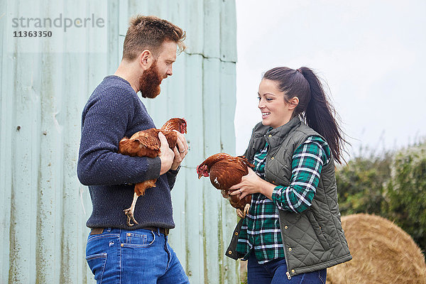 Junges Paar auf Hühnerfarm mit Hühnern