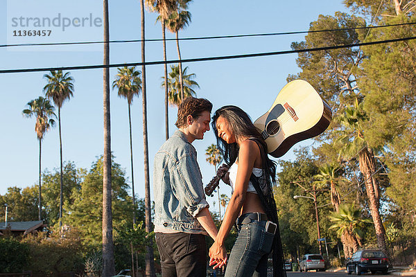 Junges Paar im Freien  von Angesicht zu Angesicht  lachend  junge Frau mit Gitarre