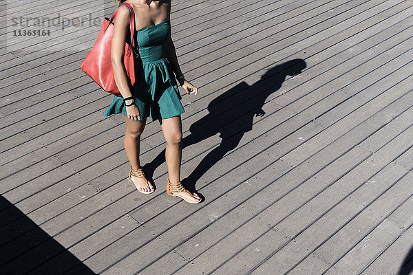 Ausschnitt einer Frau im Sonnenkleid mit Handtasche