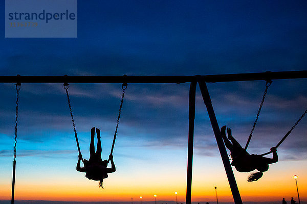 Kinder spielen auf der Schaukel bei Sonnenuntergang  Seaside Park  New Jersey  USA