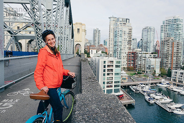 Porträt einer jungen Frau  die bereit ist  auf dem Fahrradweg Fahrrad zu fahren  Vancouver  Britisch-Kolumbien  Kanada