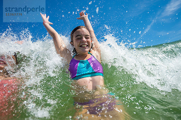 Mädchen springen vor Freude in der Meereswelle