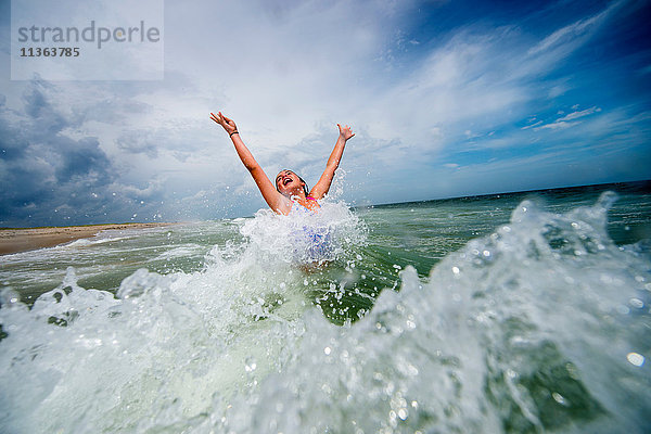 Mädchen springt vor Freude in der Meereswelle