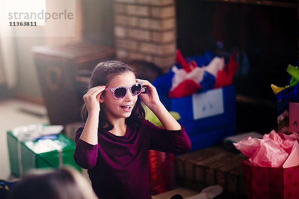 Mädchen eröffnet Geschenke  probiert eine Sonnenbrille an