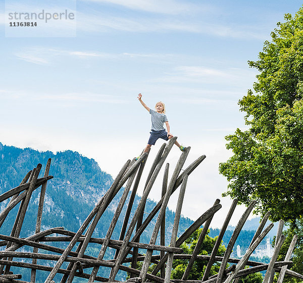 Junge steht auf einer Holzkonstruktion auf einem Spielplatz  Füssen  Bayern  Deutschland