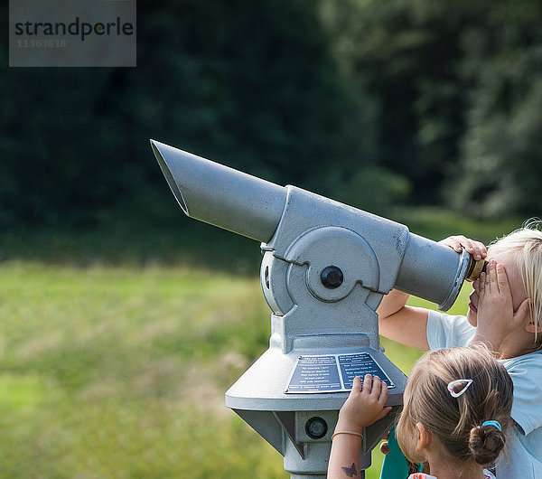 Bruder und Schwester schauen durch ein Fernglas