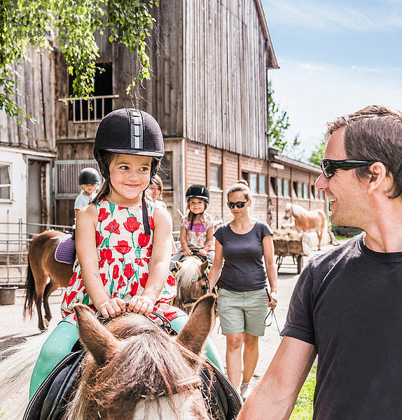 Vater führt Tochter reitendes Pferd