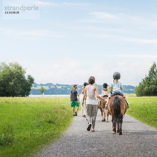 Rückansicht von Eltern  die Kinder zu Pferd führen  Füssen  Bayern  Deutschland