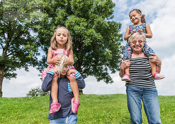 Großmutter und Enkel tragen Mädchen auf den Schultern  Füssen  Bayern  Deutschland