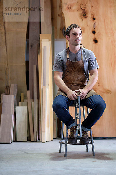 Zimmermann in seiner Werkstatt  mit Holzwerkzeug in der Hand