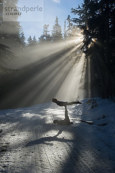 Silhouetten von Akrobaten beim Balancieren im schneebedeckten Wald  Froschteich  Mount Hood  Oregon  USA