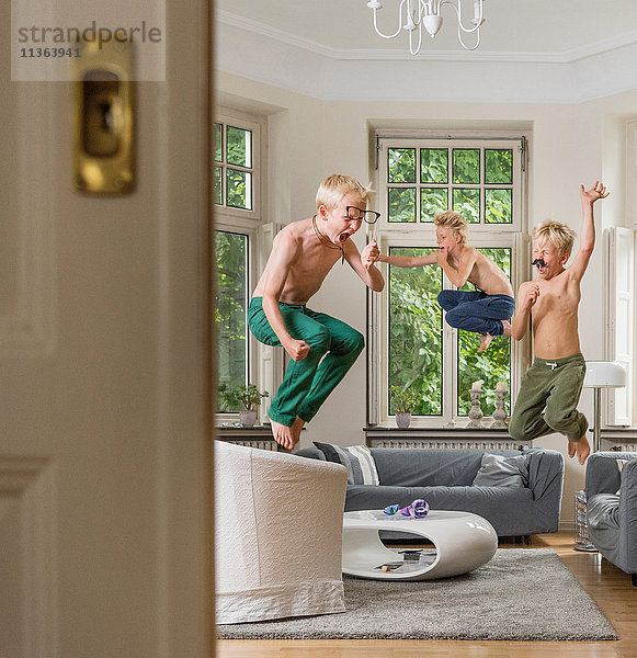 Jungen im Wohnzimmer springen in die Luft
