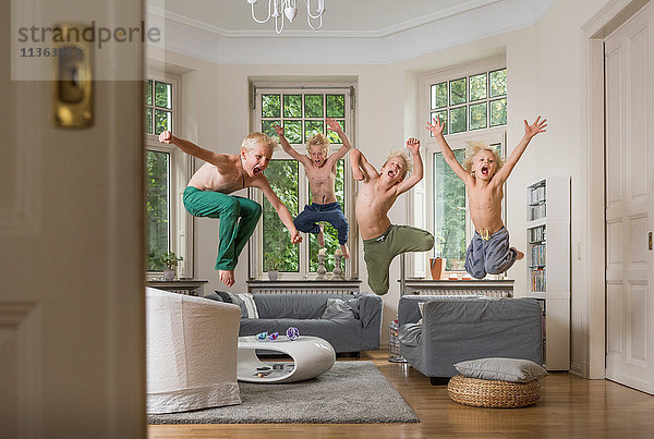 Jungen im Wohnzimmer springen in die Luft