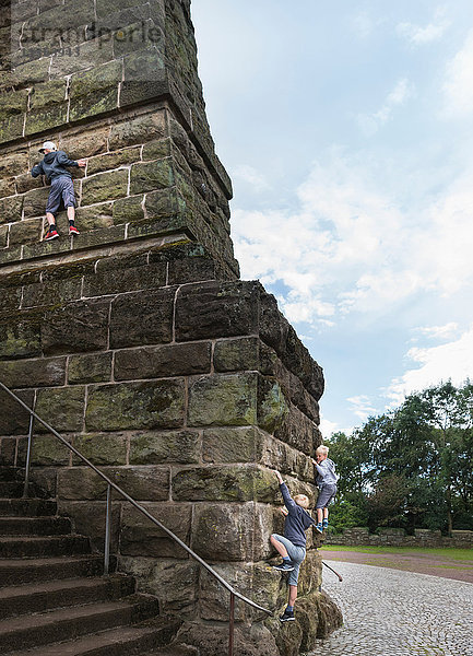 Jungen klettern an Steinwand