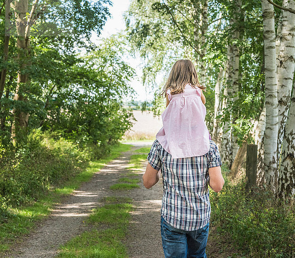 Rückansicht eines Vaters  der seine Tochter auf den Schultern trägt  Porta Westfalica  Nordrhein-Westfalen  Deutschland