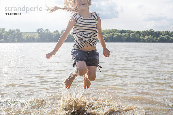 Mädchen springt und planscht im Fluss