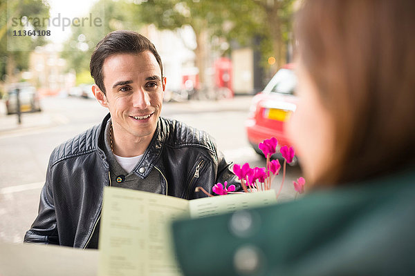 Paar im Straßencafé mit lächelndem Blick auf die Speisekarte