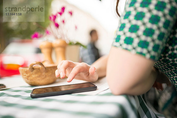 Beschnittene Ansicht der Frau im Straßencafé mit Smartphone