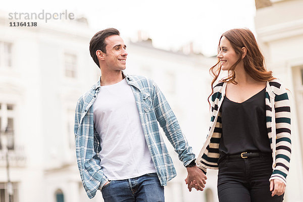 Ein Paar geht von Angesicht zu Angesicht lächelnd auf der Straße.