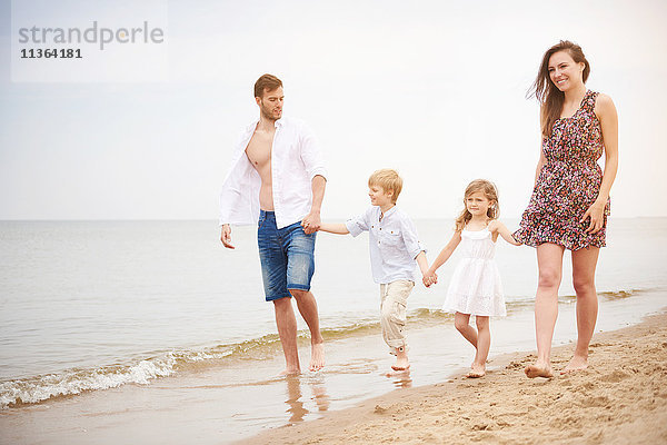 Familie hält beim Strandspaziergang Händchen