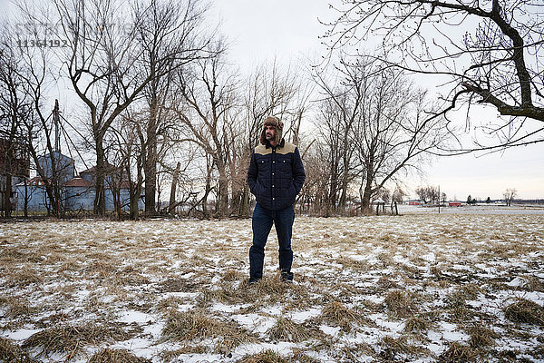 Porträt eines reifen Mannes in verschneiter ländlicher Umgebung  der einen Trapperhut trägt