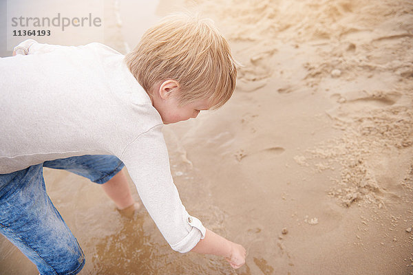 Junge zeichnet im Sand
