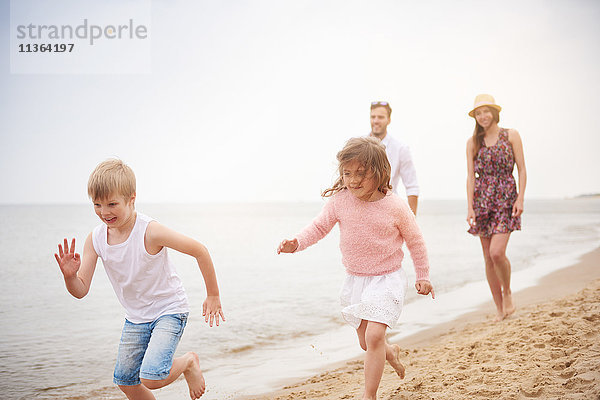 Familie läuft am Sandstrand entlang