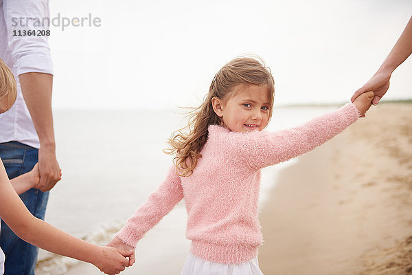 Familie hält beim Strandspaziergang Händchen