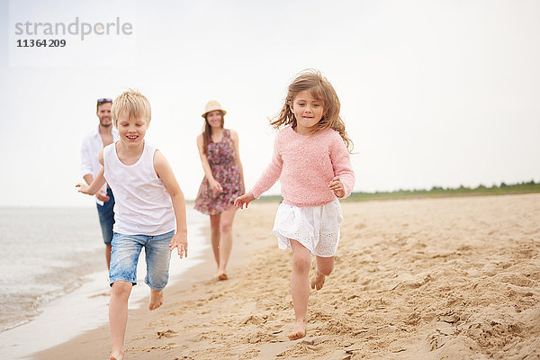 Familie läuft am Sandstrand entlang