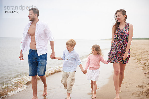 Familie hält beim Strandspaziergang Händchen