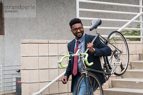 Junger Mann trägt Fahrrad die Treppe hinunter